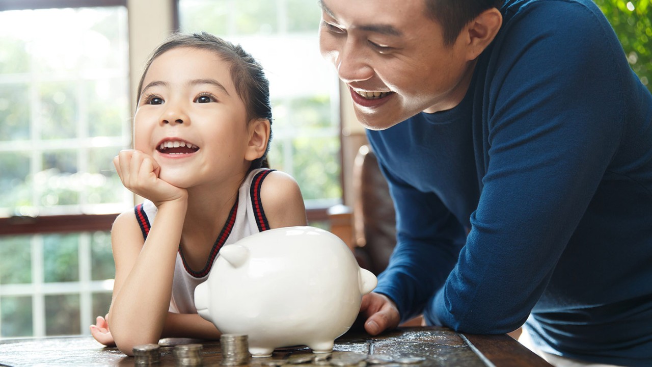 Father teaching daughter to save; image used for HSBC Philippines Gold Visa Cash Back Credit Card page